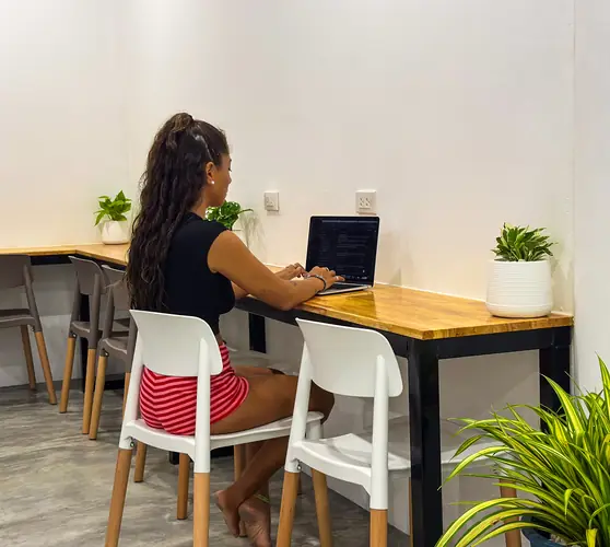 Una huésped trabaja con su portátil en el largo mostrador de madera del coworking