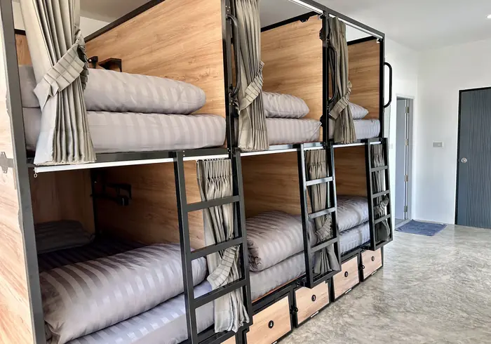 Six numbered bunks in a row with privacy curtains and storage drawers