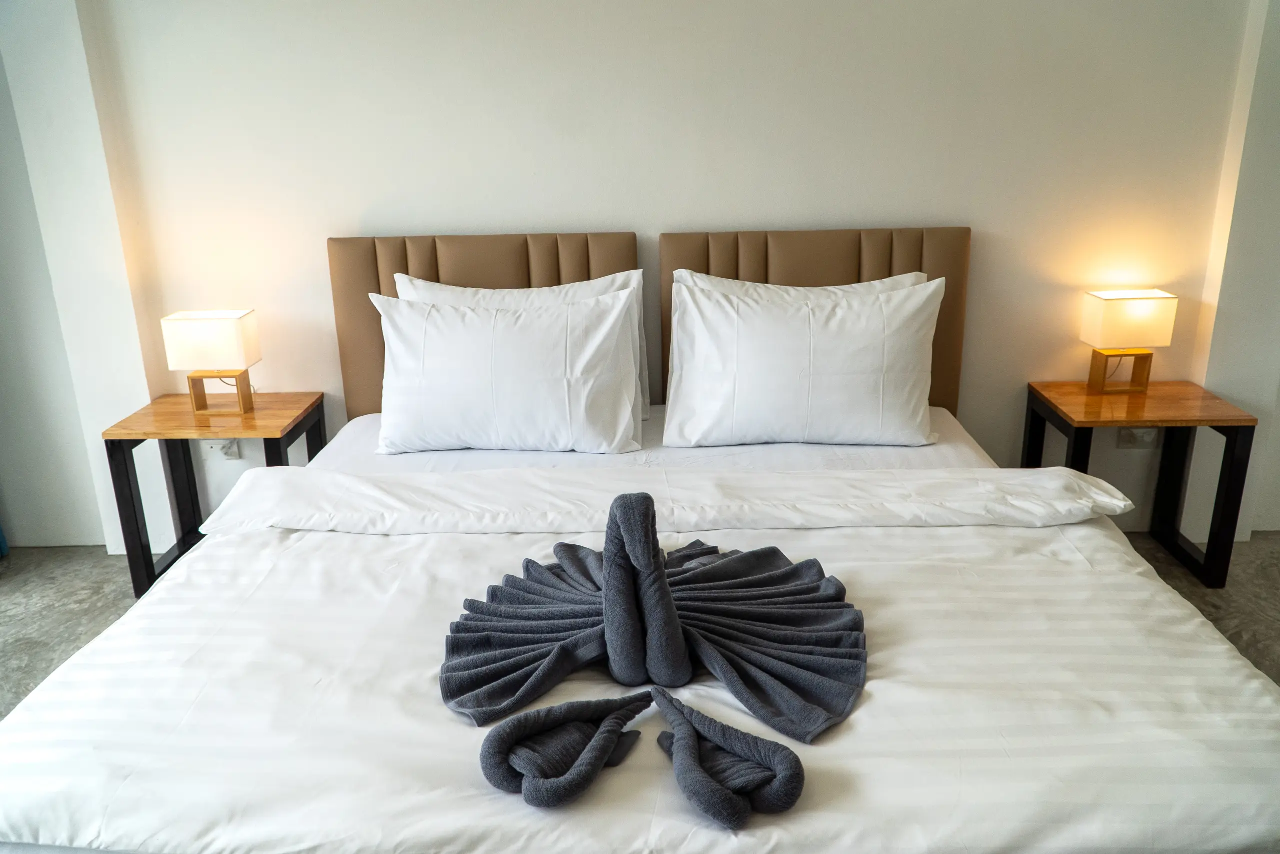 Peacock towel sculpture spread across the bed between two lamps