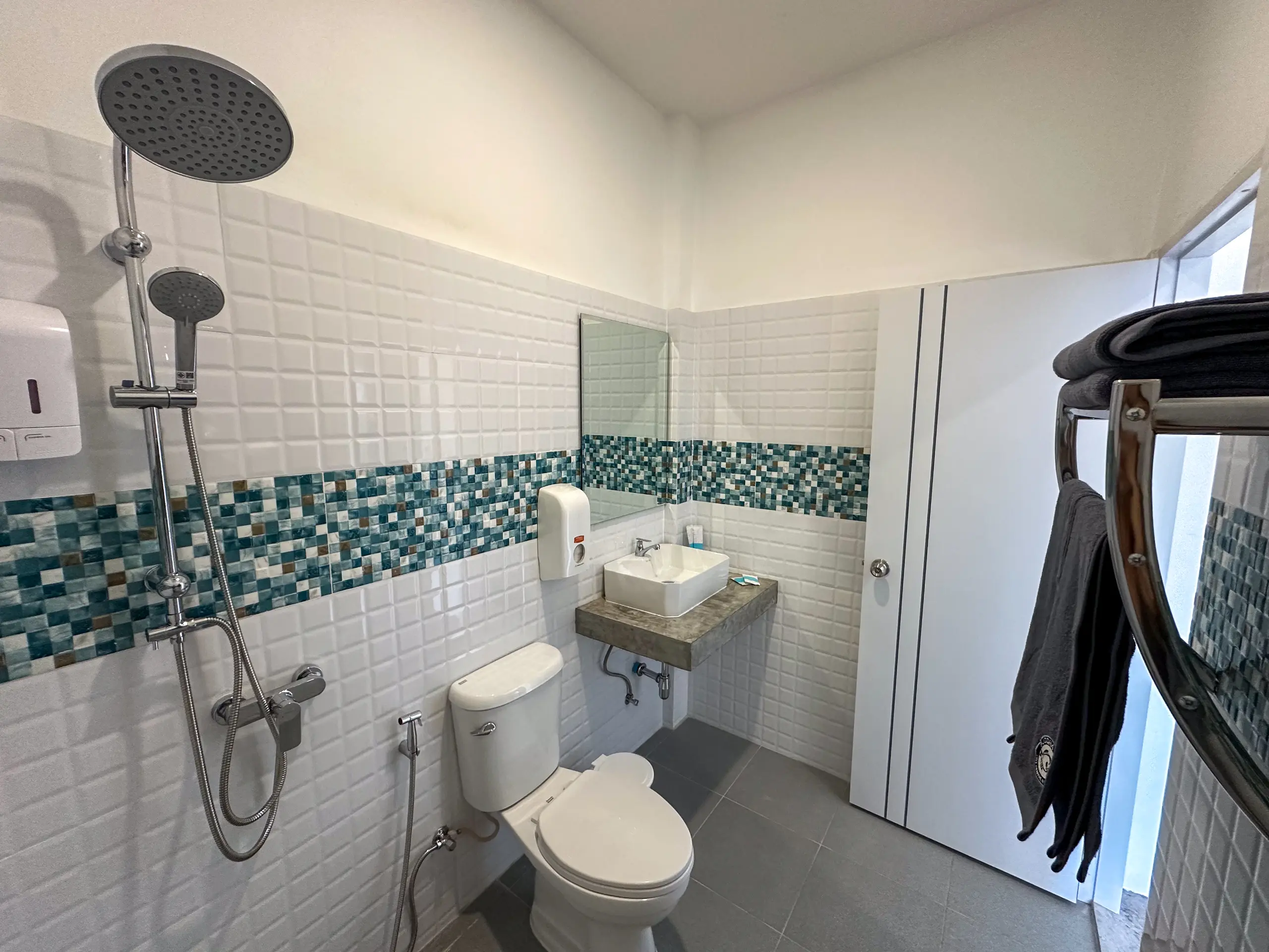 Private bathroom with rain shower and turquoise mosaic band