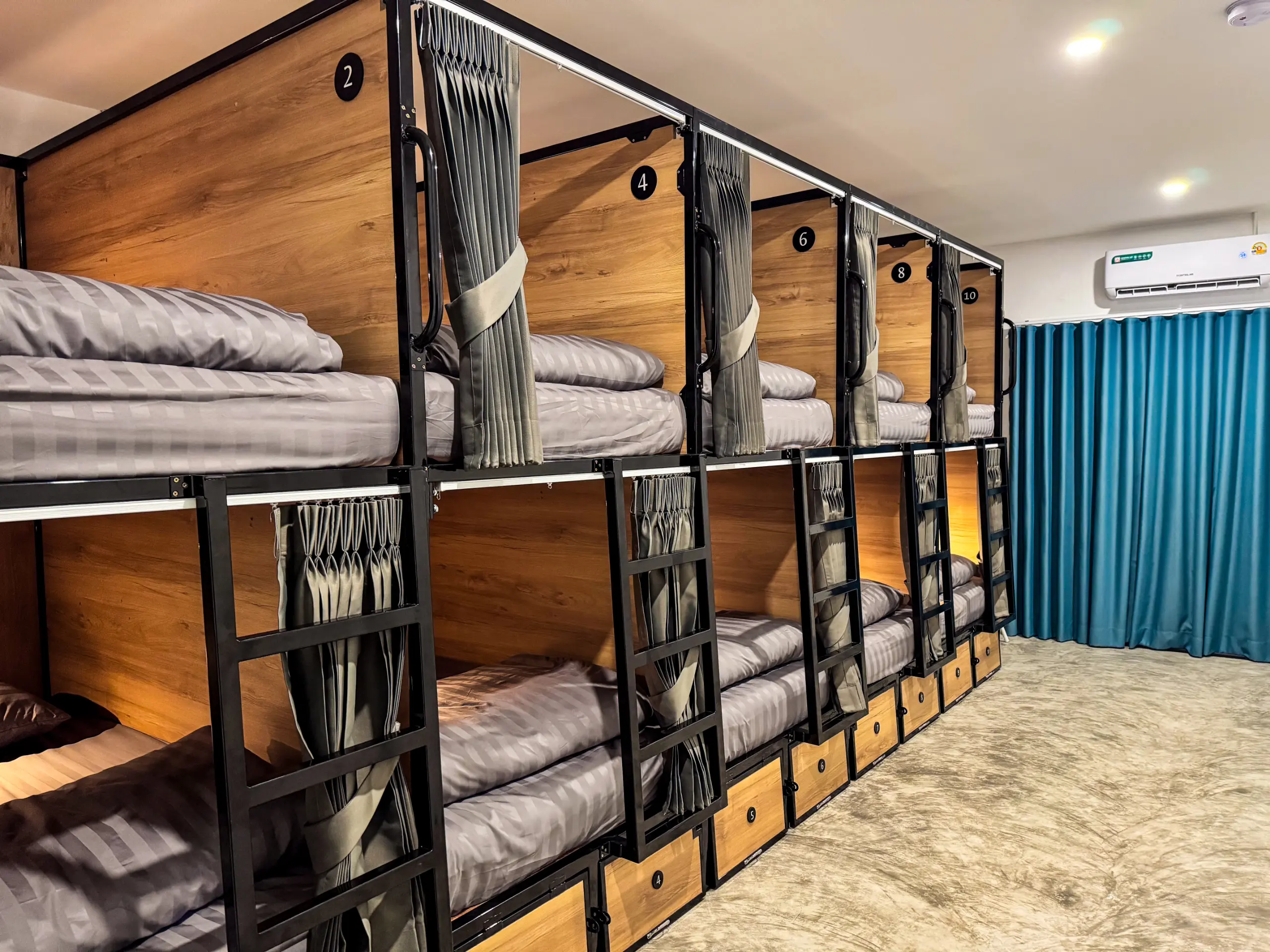 Capsule pods along the wall with air conditioning and teal curtain